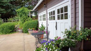 Une maison avec un patio couvert, une table et des plantes en pot.