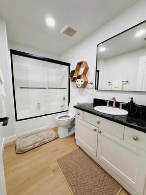 Un bagno moderno con uno specchio grande, mobili bianchi e un piano di lavoro nero.
