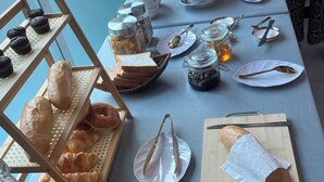En frukostbuffé med bröd, bakverk och olika tillbehör.