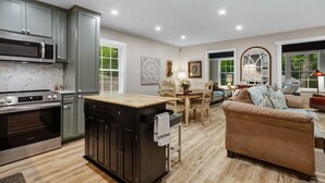 Una cucina moderna con elettrodomestici integrati, un'area pranzo con tavolo e sedie in legno e un accogliente soggiorno con divano e camino.