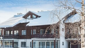 Un immeuble à plusieurs étages, dont le toit est recouvert de neige et qui possède un balcon.