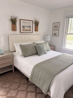 A bedroom with a large bed, two bedside tables, a window, and wall-mounted decor.