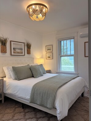 A bedroom with a bed, bedside tables, a window, and wall-mounted decor.