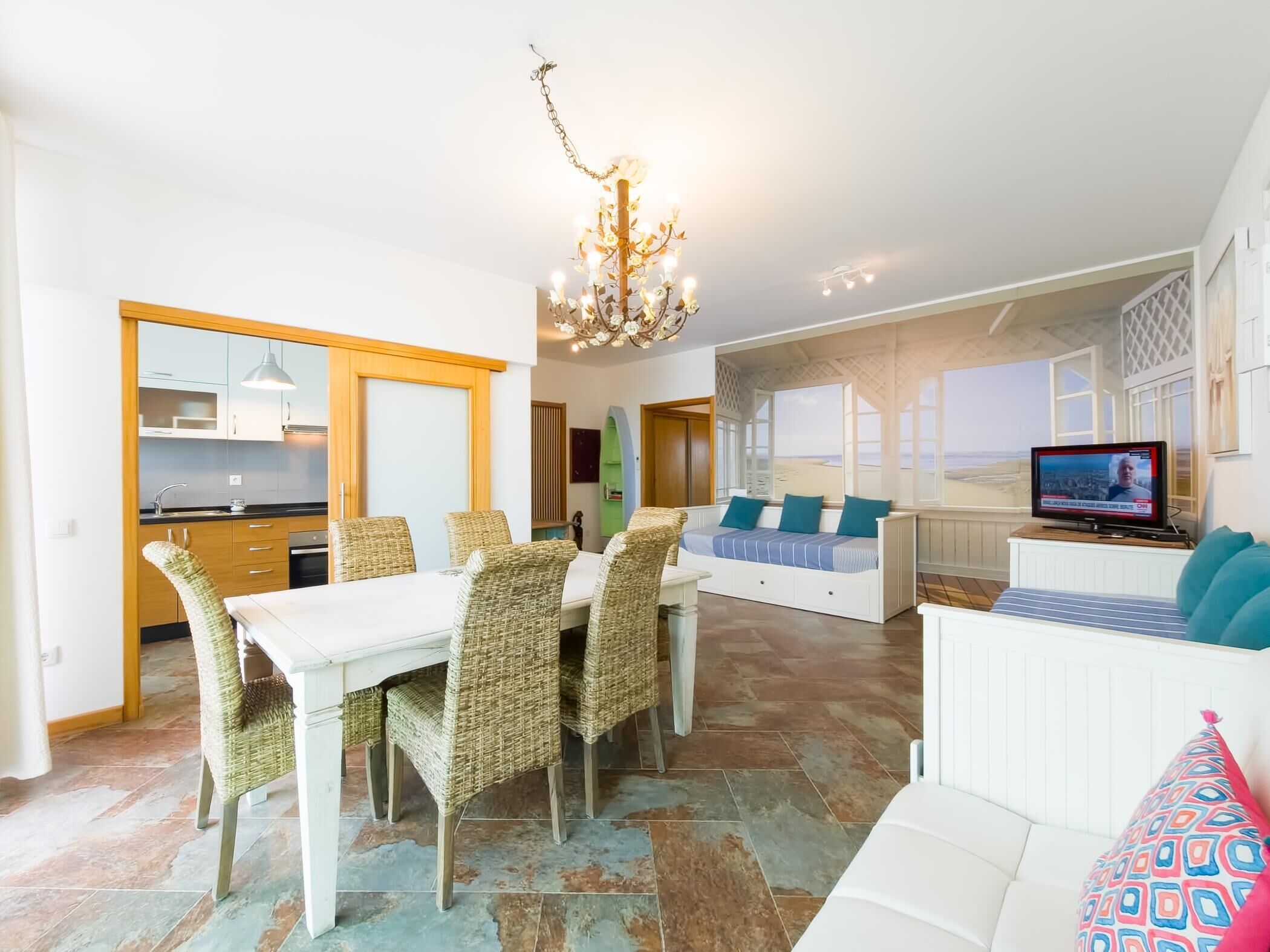 Een moderne woonkamer met een eethoek, een televisie en uitzicht op zee.