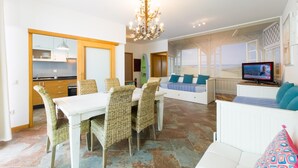 Ein modernes Wohnzimmer mit Essbereich, Fernseher und Meerblick.