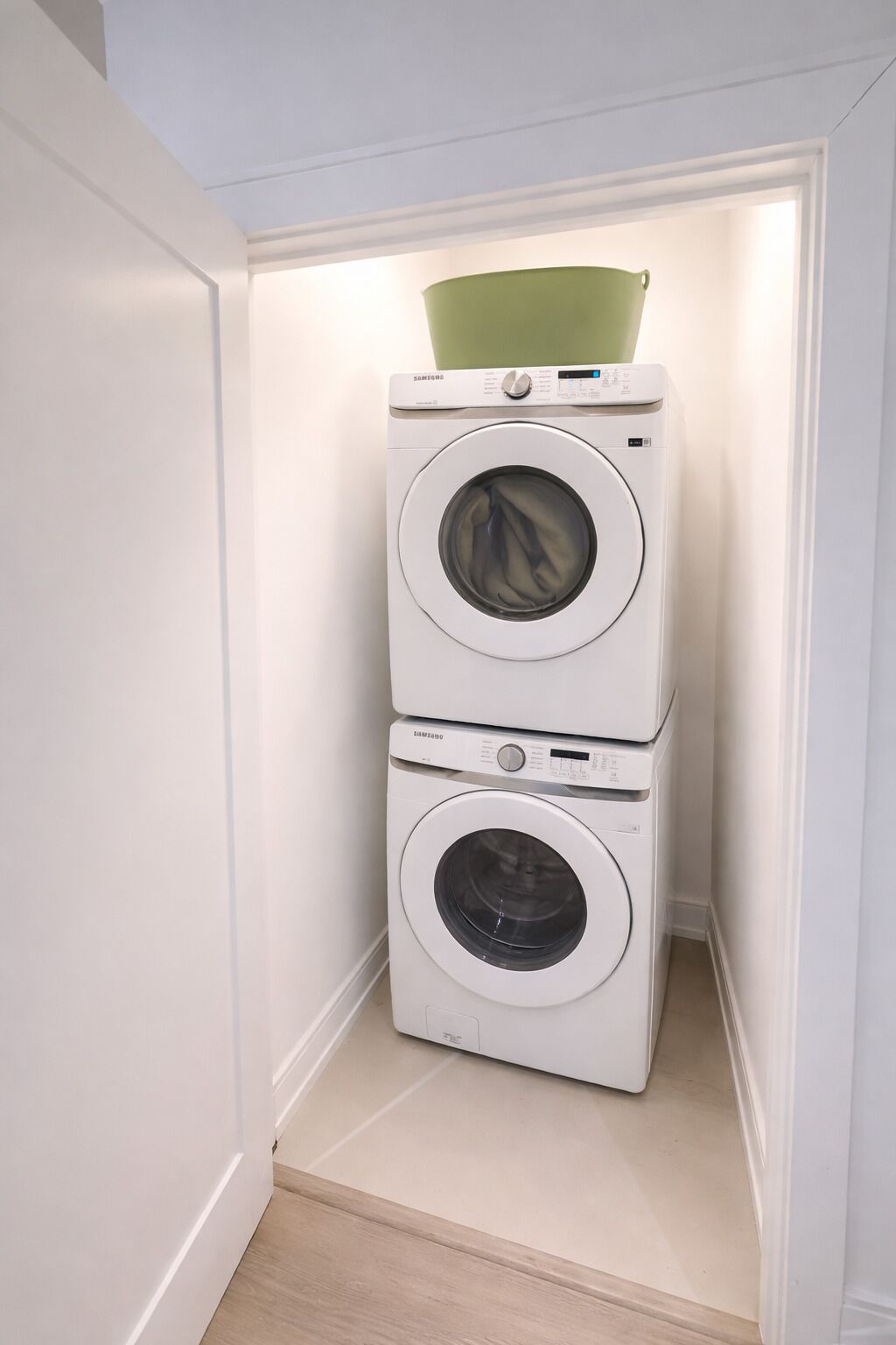 A compact laundry room with two stacked front-loading washing machines.