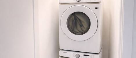 A compact laundry room with two stacked front-loading washing machines.