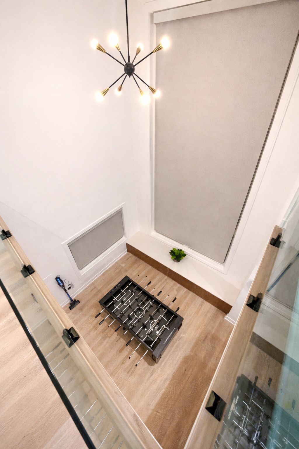 A modern room with a foosball table, a ceiling light fixture, and a small plant on the floor.