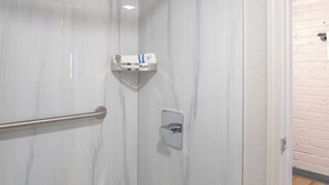 A modern bathroom with a shower, marble walls, and a wooden floor. - Economy Suites Springfield - Fairgrounds (Springfield)