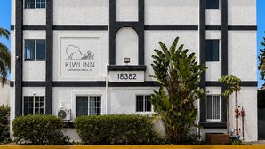 Un hotel con fachada blanca, detalles en negro y un letrero que dice 'KIWI INN'.