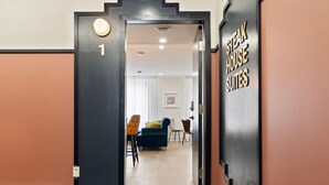 A hotel entrance with a modern design, featuring a number '1' sign, a staircase, and a sign indicating 'STEAK HOUSE SUITES'. - Elegant Historic Suite | Two Floors of Luxury (Montreal)