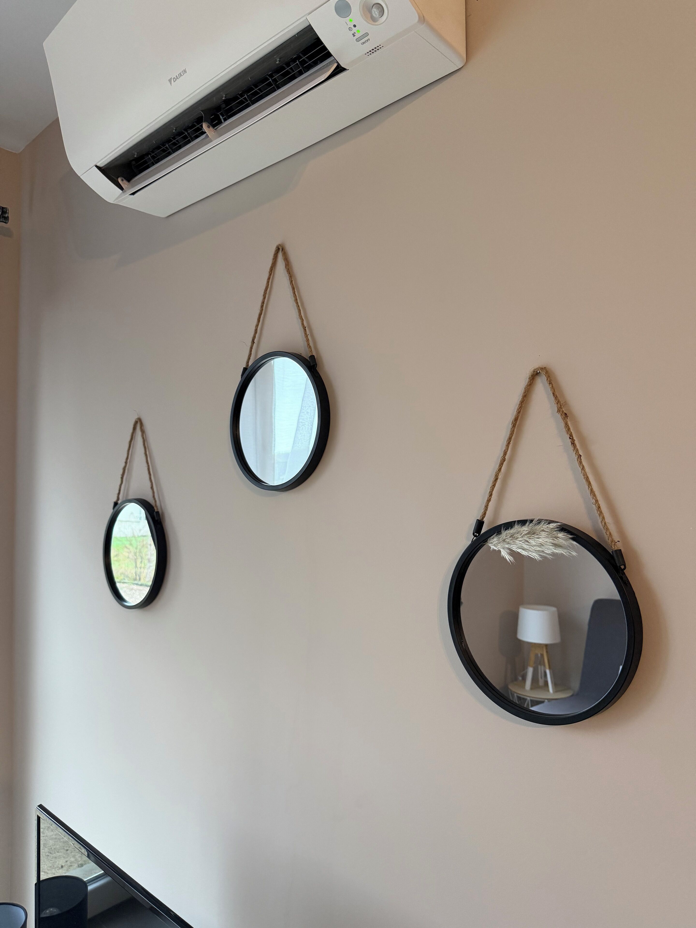 Un climatiseur fixé au mur, deux miroirs muraux et une lampe.