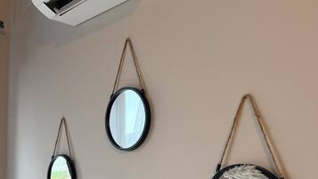Un climatiseur fixé au mur, deux miroirs muraux et une lampe.