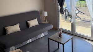 Ett modernt vardagsrum med en mörkgrå soffa, ett litet träbord och en hängande lampa.