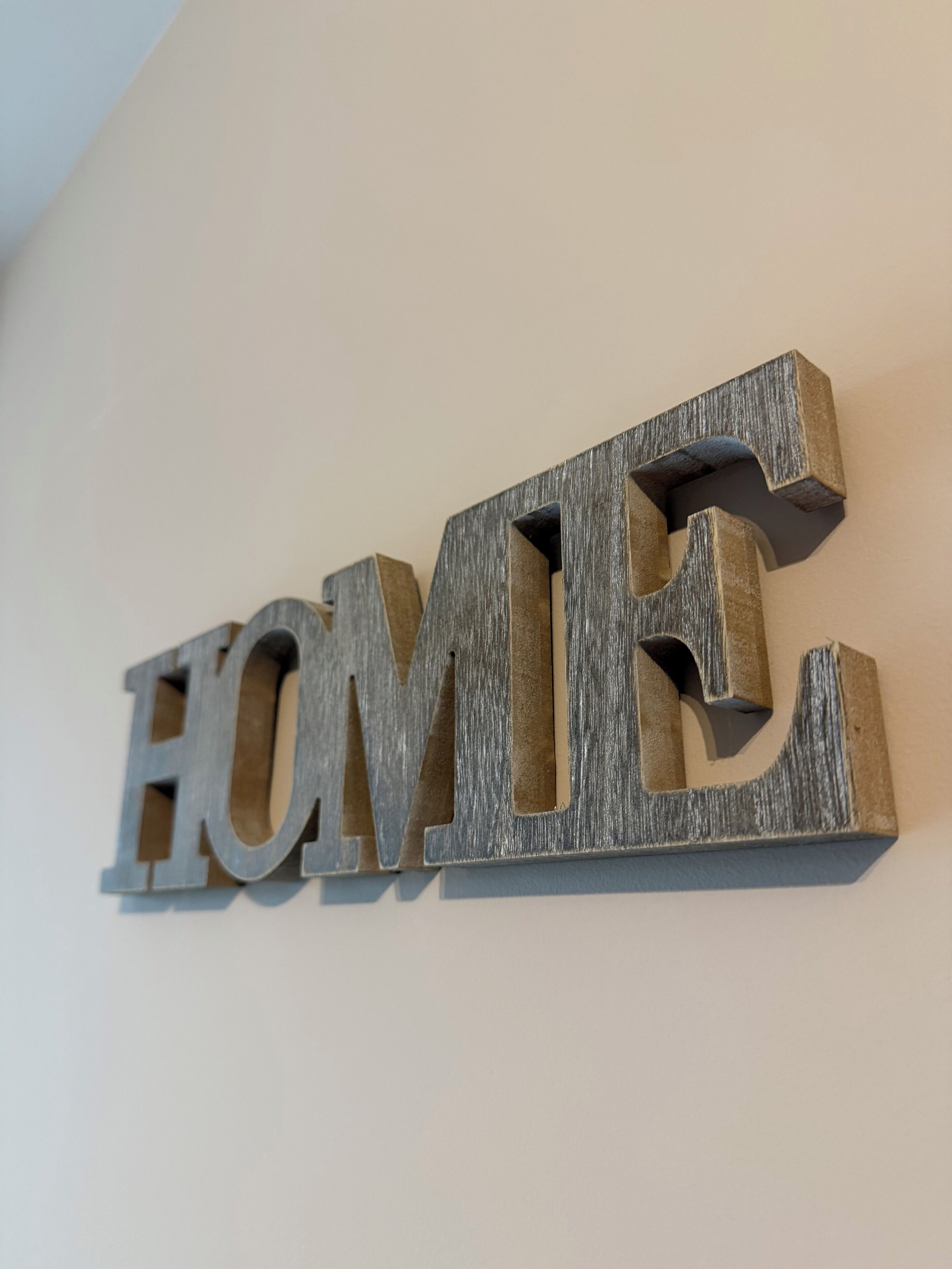 A wooden sign with the word "HOME" mounted on a wall.