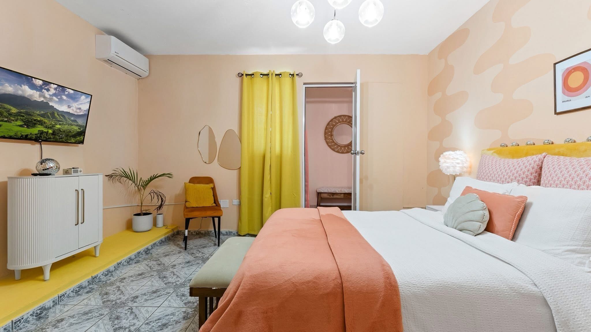 A bedroom with a bed, a TV, a wardrobe, a mirror, and a door.