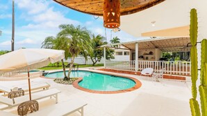 A pool area with a circular pool, lounge chairs, and a covered seating area. - Unique Retro house with pool (Aguadilla)