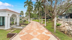 A pathway leading to a building with a tiled roof and a covered outdoor area. - Unique Retro house with pool (Aguadilla)
