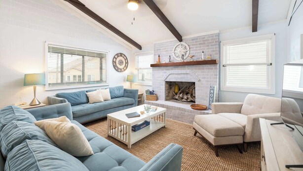 A living room with a fireplace, blue and white sofas, a coffee table, and a television. - New Listing! Walk to Beach, Hot Tub & Games! (Kill Devil Hills)
