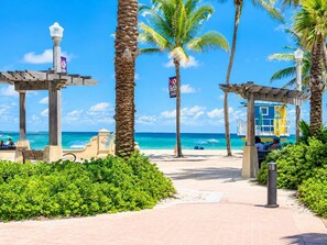 A beachside walkway with palm trees, a lifeguard tower, and a clear view of the ocean. - A Coastal Nest by the Sea  Studio in a Prime Location (Hollywood)