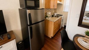 Une cuisine compacte équipée d’un réfrigérateur, d’un four à micro-ondes, d’une machine à café et d’une cuisinière.