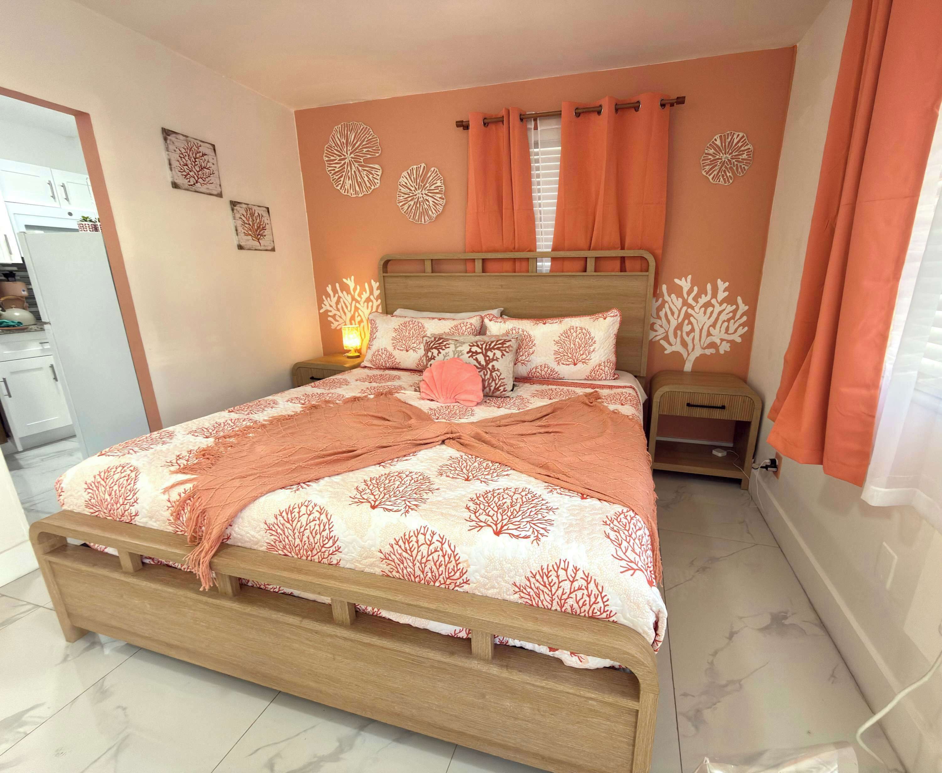 A bedroom with a wooden bed, orange curtains, and coral-themed wall decor.