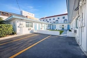 A clean, modern hotel with a parking lot and a small garden area. - Cozy Beach Studio | Workspace, Kitchen & Pets OK (Hollywood)