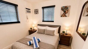 Ein ordentlich eingerichtetes Schlafzimmer mit Bett, Nachttischen, Lampen, einem Spiegel und Bildern an den Wänden.
