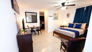 Ein Hotelzimmer mit Bett, Schreibtisch, Stuhl, Deckenventilator und Essbereich.
