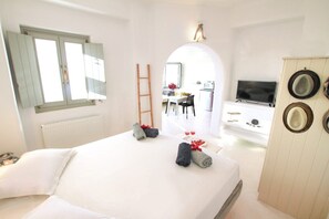 Una camera d'albergo con un letto, una scrivania, una televisione e un armadio.
