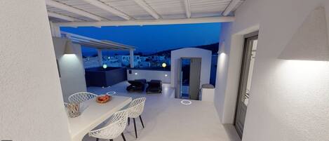 Terraza en la azotea con zona de comedor, dos sillones de relax y vistas a la ciudad al anochecer.