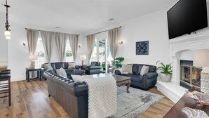 A living room with a leather sofa, a coffee table, and a fireplace. - Paso del Sol |Pool Table, fire pit (Paso Robles)