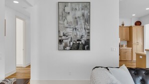 A modern living room with a large abstract painting, a leather sofa, and a wooden floor. - Paso del Sol |Pool Table, fire pit (Paso Robles)