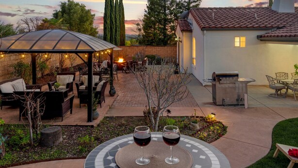 A patio area with outdoor seating, a covered seating area, and a table with two glasses of red wine. - Paso del Sol |Pool Table, fire pit (Paso Robles)
