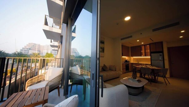 A modern apartment with a balcony, a dining area, and a kitchen. - Dubai Hills Apt with Infinity Pool (Dubai)
