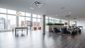 En rymlig entréhall med modern design, med en stor sittgrupp bestående av soffor och fåtöljer, ett soffbord och en receptionsdisk med en växt.