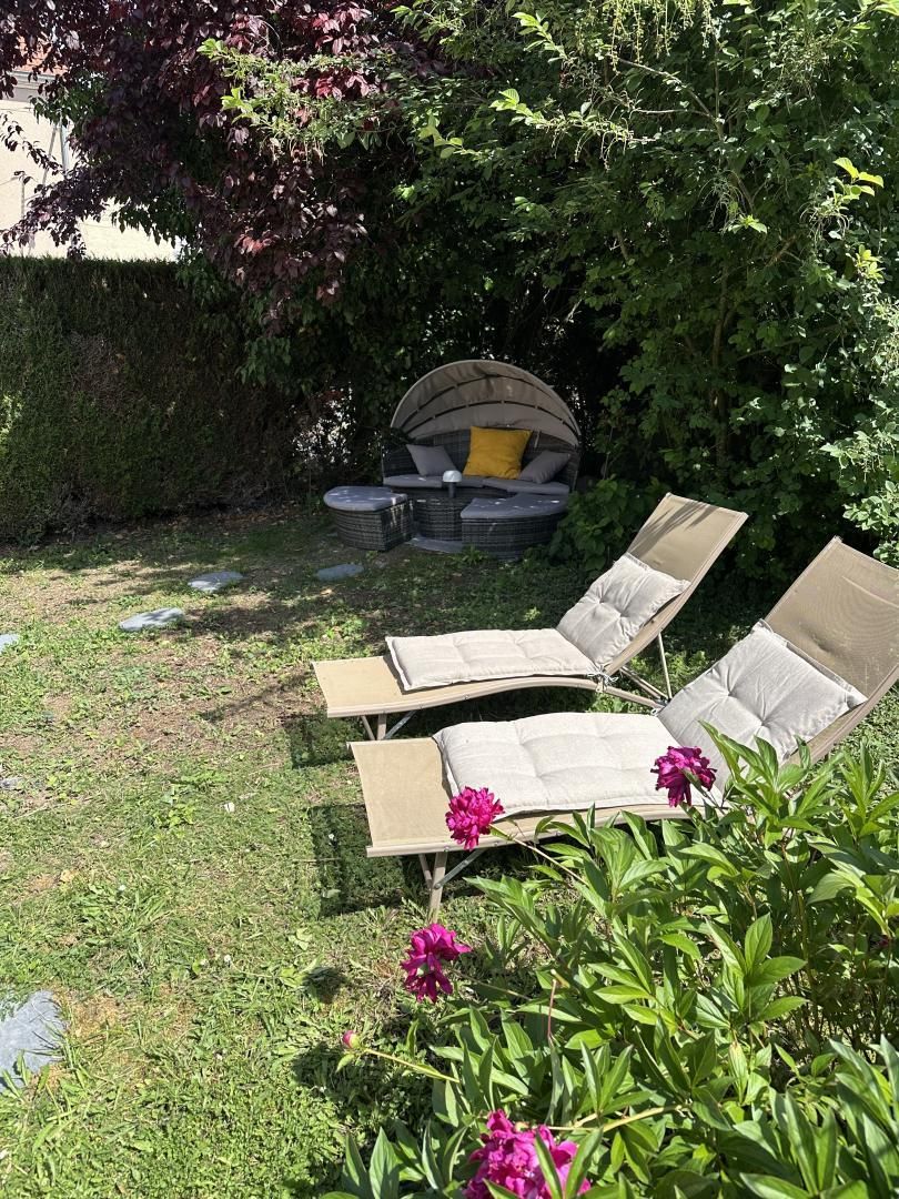 A garden with a seating area, including a swing chair and lounge chairs.