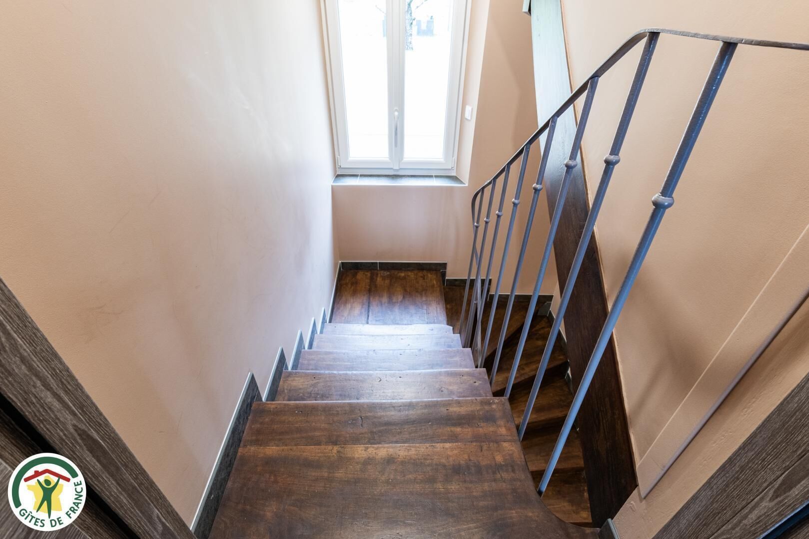 Un escalier en bois avec des rampes en métal menant à un palier.