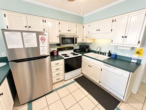 A kitchen with white cabinets, a stainless steel refrigerator, a microwave, a stove, and a dishwasher. - Ocean View 2BR + Steps from the Beach + Pool (Myrtle Beach)