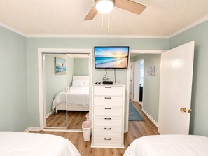 Ein Schlafzimmer mit einem Bett, einem Schminktisch, einem Fernseher und einem Deckenventilator.