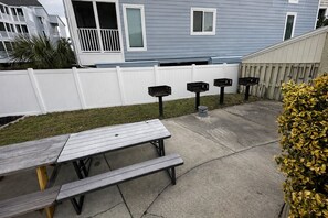 A backyard with a picnic table, a white fence, and a mailbox. - Ocean View Condo Steps from the Beach (Myrtle Beach)