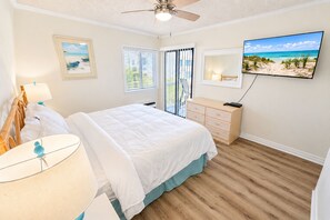 A bedroom with a bed, a dresser, a television, and a ceiling fan. - Ocean View 2BR + Steps from the Beach + Pool (Myrtle Beach)