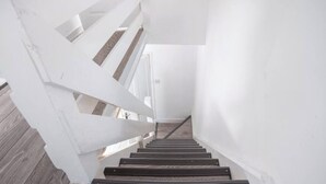 A staircase with white railings and wooden steps leading to an upper floor.