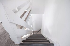 Una escalera con barandas blancas y peldaños de madera que sube a un piso superior.