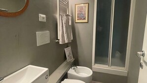 Un baño moderno con un espejo grande, un lavamanos, un inodoro y una ducha.
