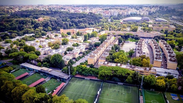 Vista aérea de una zona residencial con varios edificios de apartamentos, campos deportivos y un estadio.