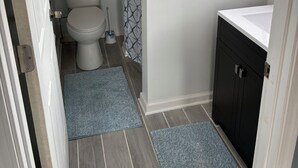 A small bathroom with a toilet, a sink, and a shower curtain. - Quaint Studio Unit in fantastic Beecher with refreshing AC (Beecher)