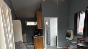 A spacious living area with a large sectional sofa, a kitchen in the background, and a dining area with a table and chairs. - Quaint Studio Unit in fantastic Beecher with refreshing AC (Beecher)
