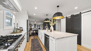 A modern kitchen with white cabinetry, a central island, and pendant lighting. - Luxury Franklin Retreat • Walk to Downtown • Front Porch (Franklin)