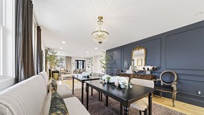 A modern living room with a dark accent wall, a chandelier, a dining table with floral centerpieces, and a large mirror. - Luxury Franklin Retreat • Walk to Downtown • Front Porch (Franklin)